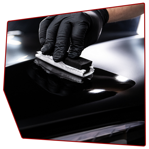 Black-gloved hand applying ceramic coating to a shiny black car surface with applicator pad. Black-gloved hand applying ceramic coating to a shiny black car surface with applicator pad.