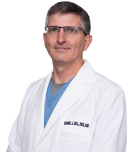 A man wearing a white lab coat and glasses is standing in front of a white background.