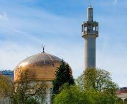 A mosque with a dome and a minaret surrounded by trees.