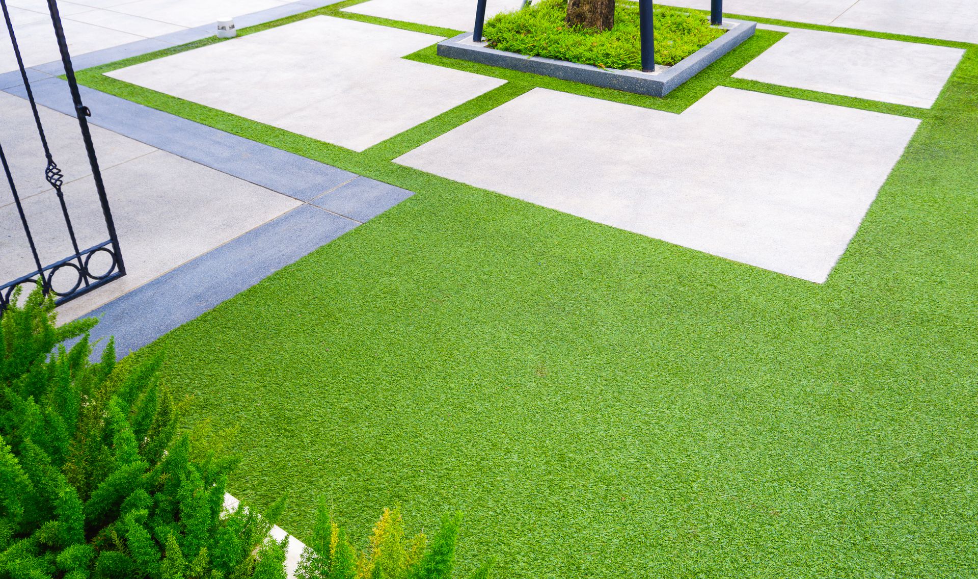 Green grass lawn with white concrete stepping stones and a metal gate edge in the corner