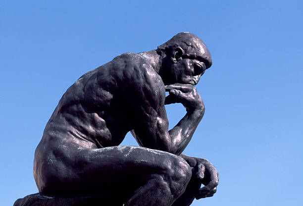 The Thinker statue silhouetted against a clear blue sky