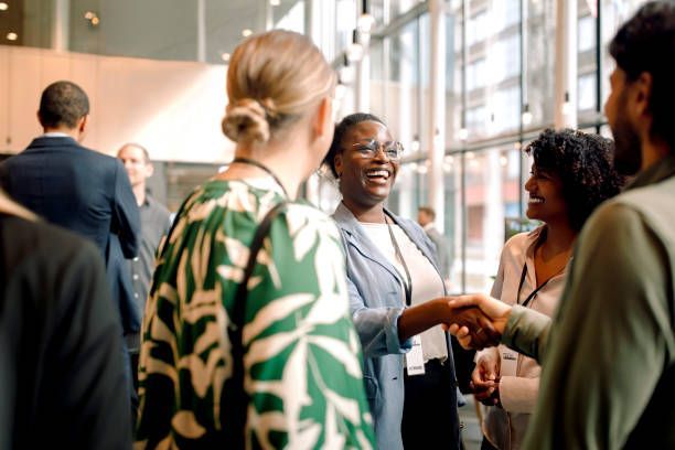 People chatting and shaking hands in a bright indoor networking event.