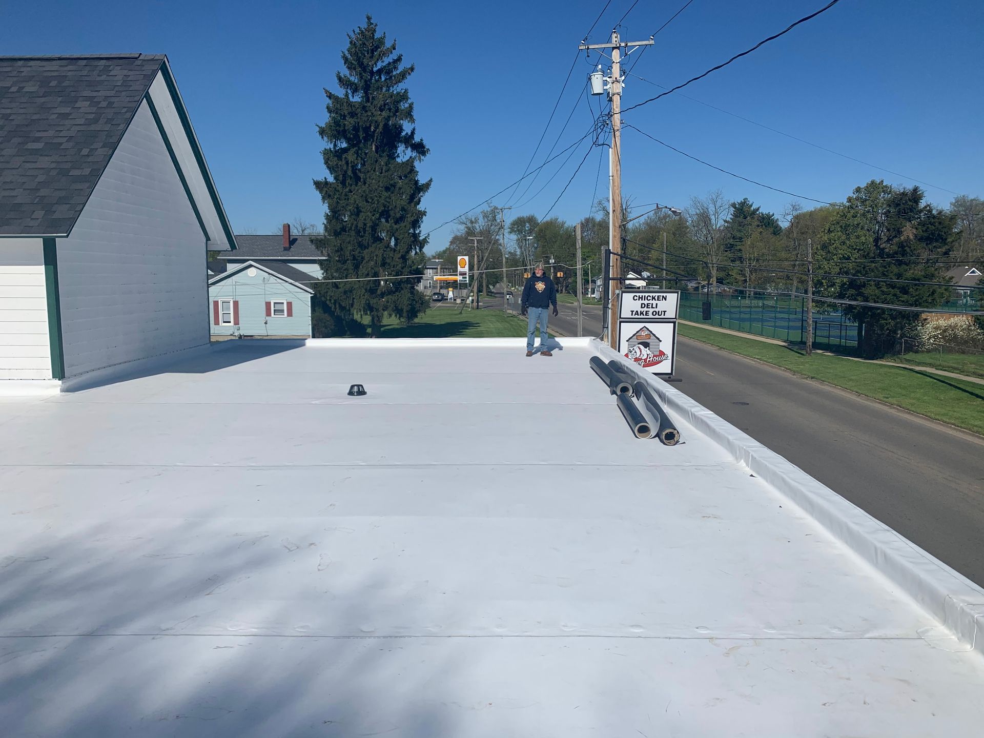 Residential street with a lone person near a utility pole on a bright sunny day.