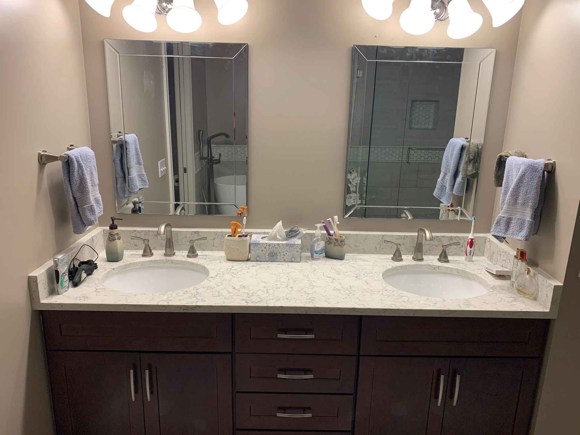 Double vanity bathroom with two sinks, large mirrors, towel bars, and marble countertop