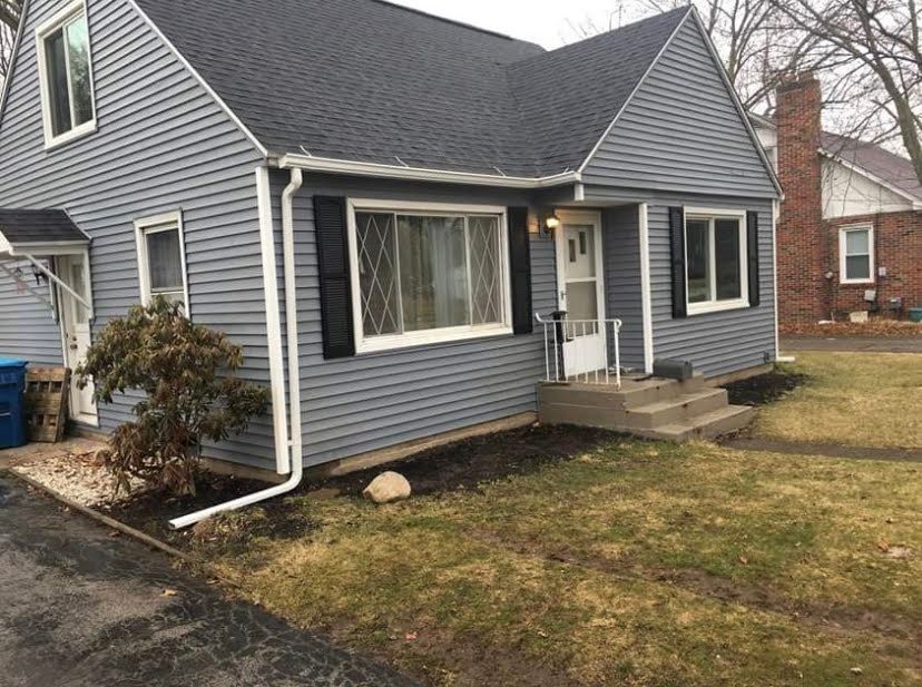 Gray house exterior with black shutters, white trim, and a small front porch.