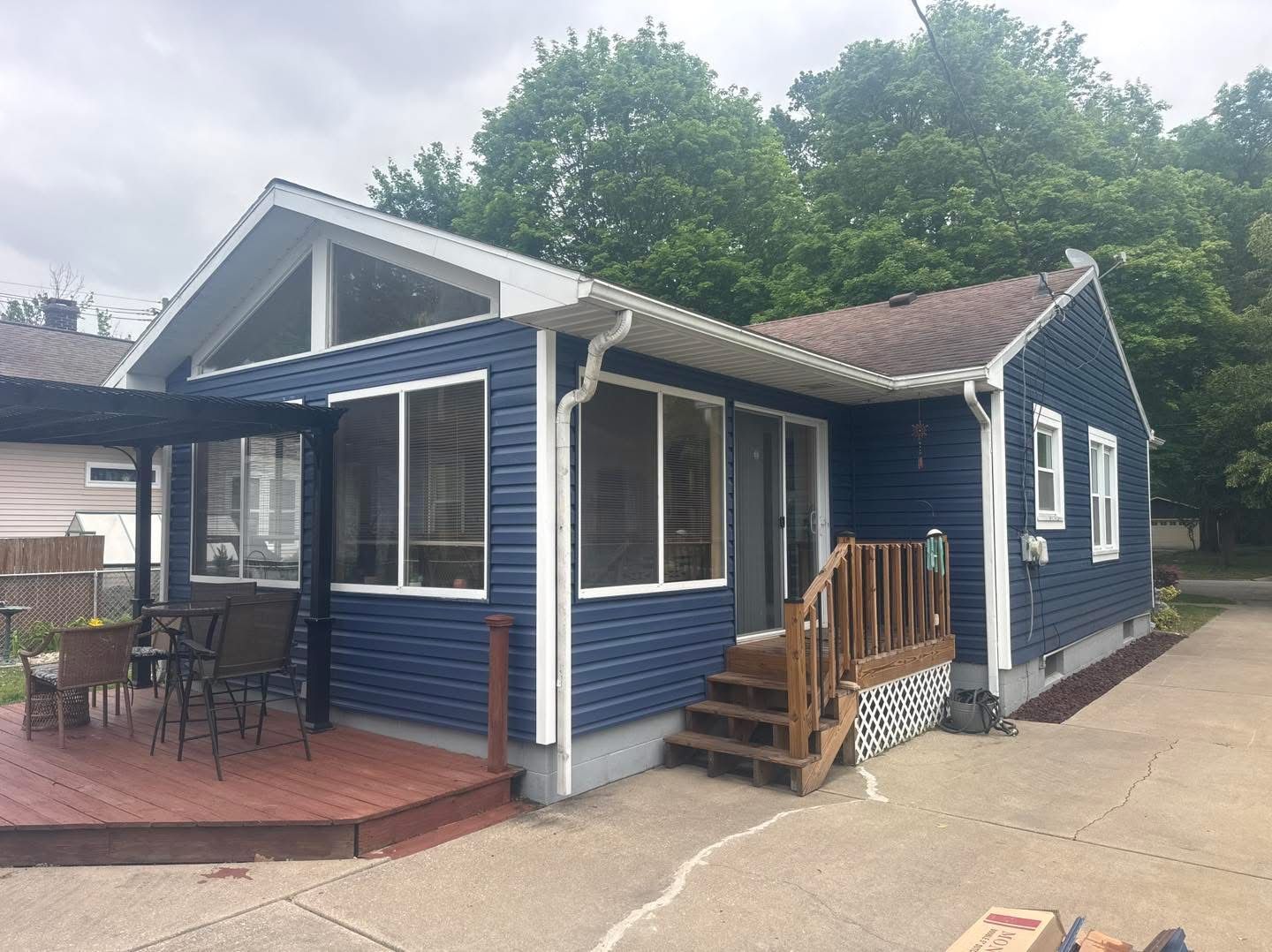 Blue house with a covered porch, white trim, and wooden steps beside a driveway