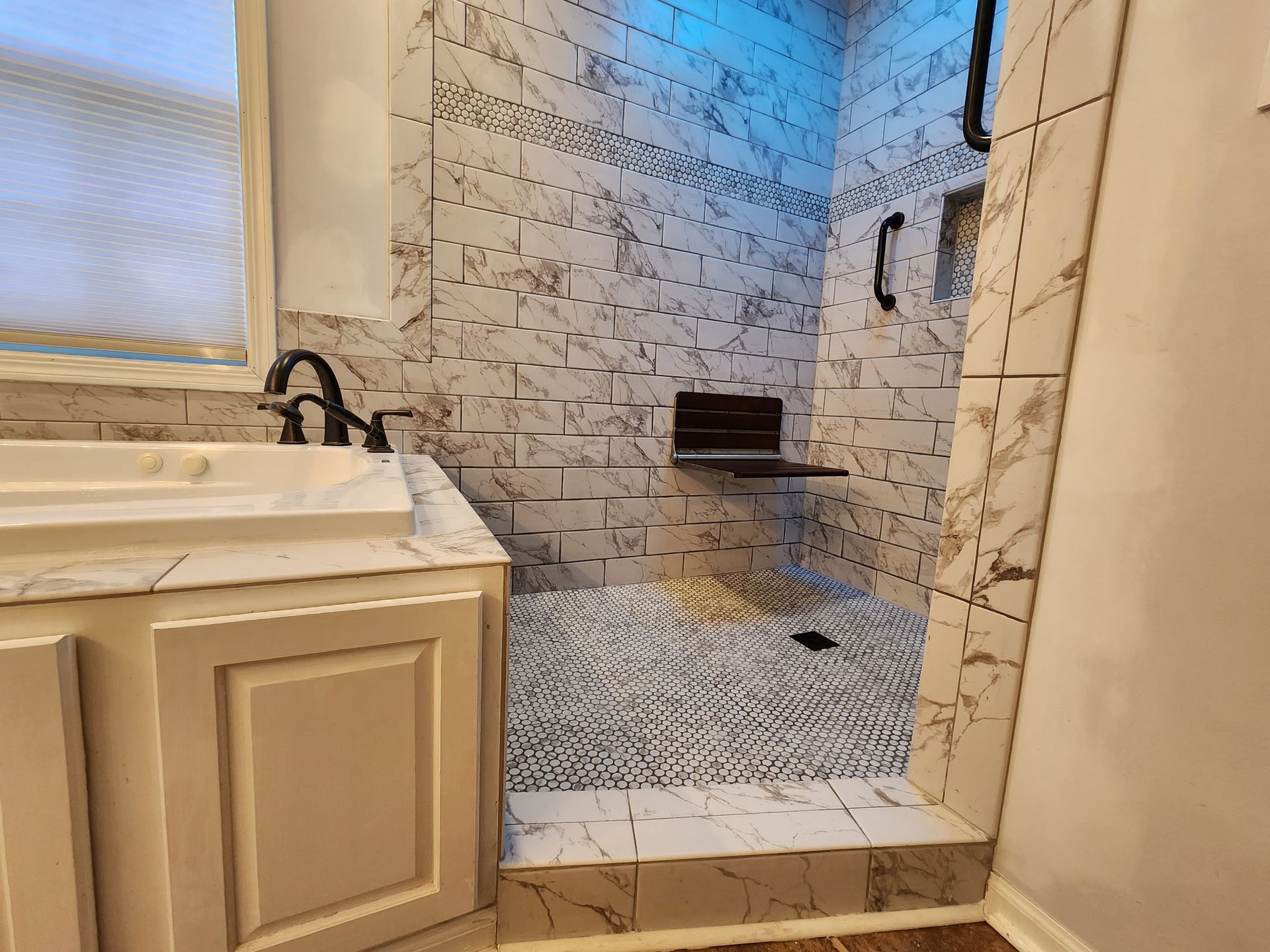 Modern bathroom with a glass-enclosed tiled shower, vanity sink, and small window