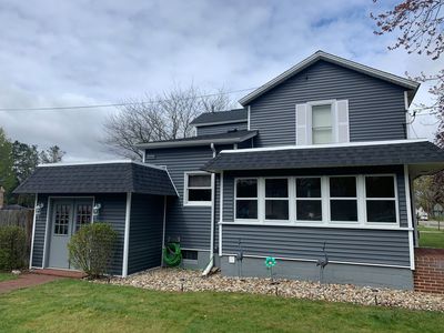 Gray two-story house with black trim and a small front porch under an overcast sky