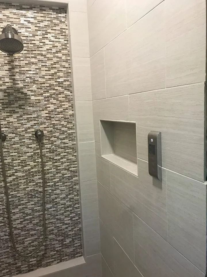 Modern shower with tiled walls, mosaic accent strip, and built-in wall niche next to a showerhead.