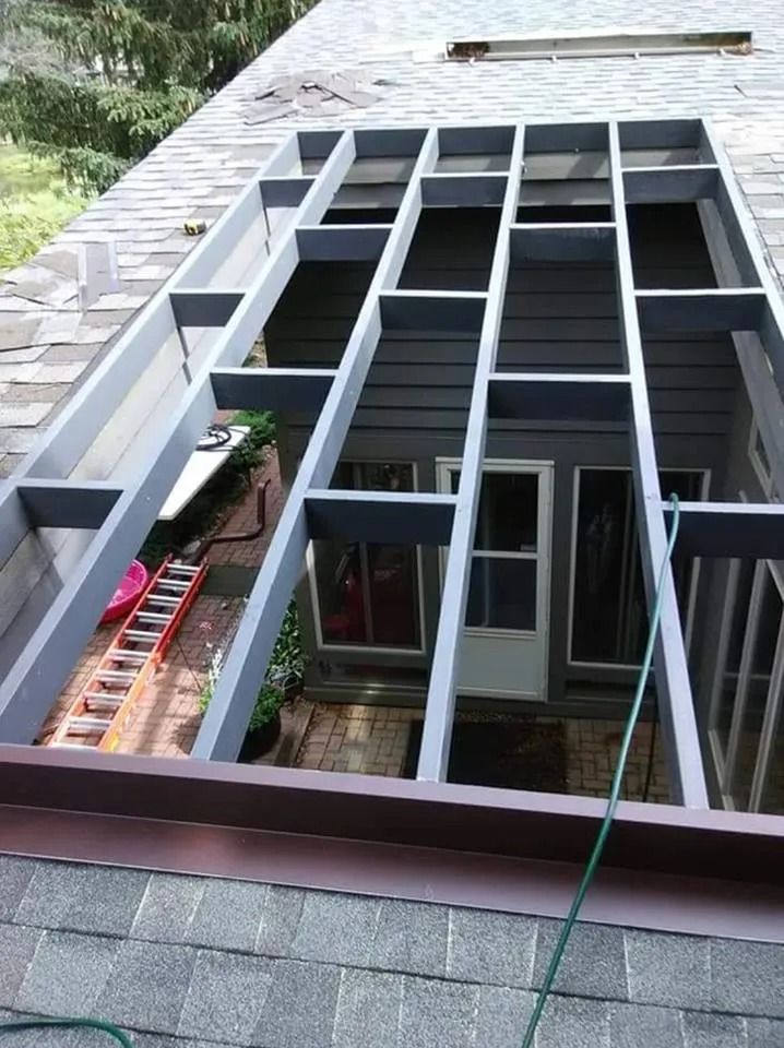 Gray metal frame scaffolding against a house exterior with windows and roof shingles under construction