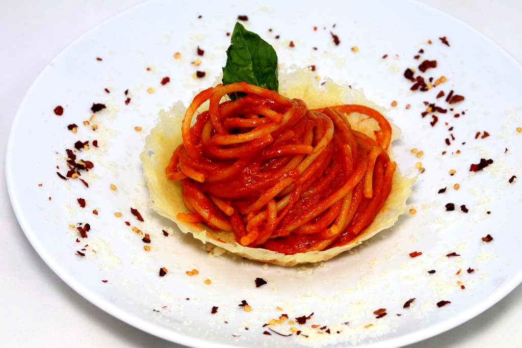 Un piatto bianco condito con spaghetti e salsa di pomodoro