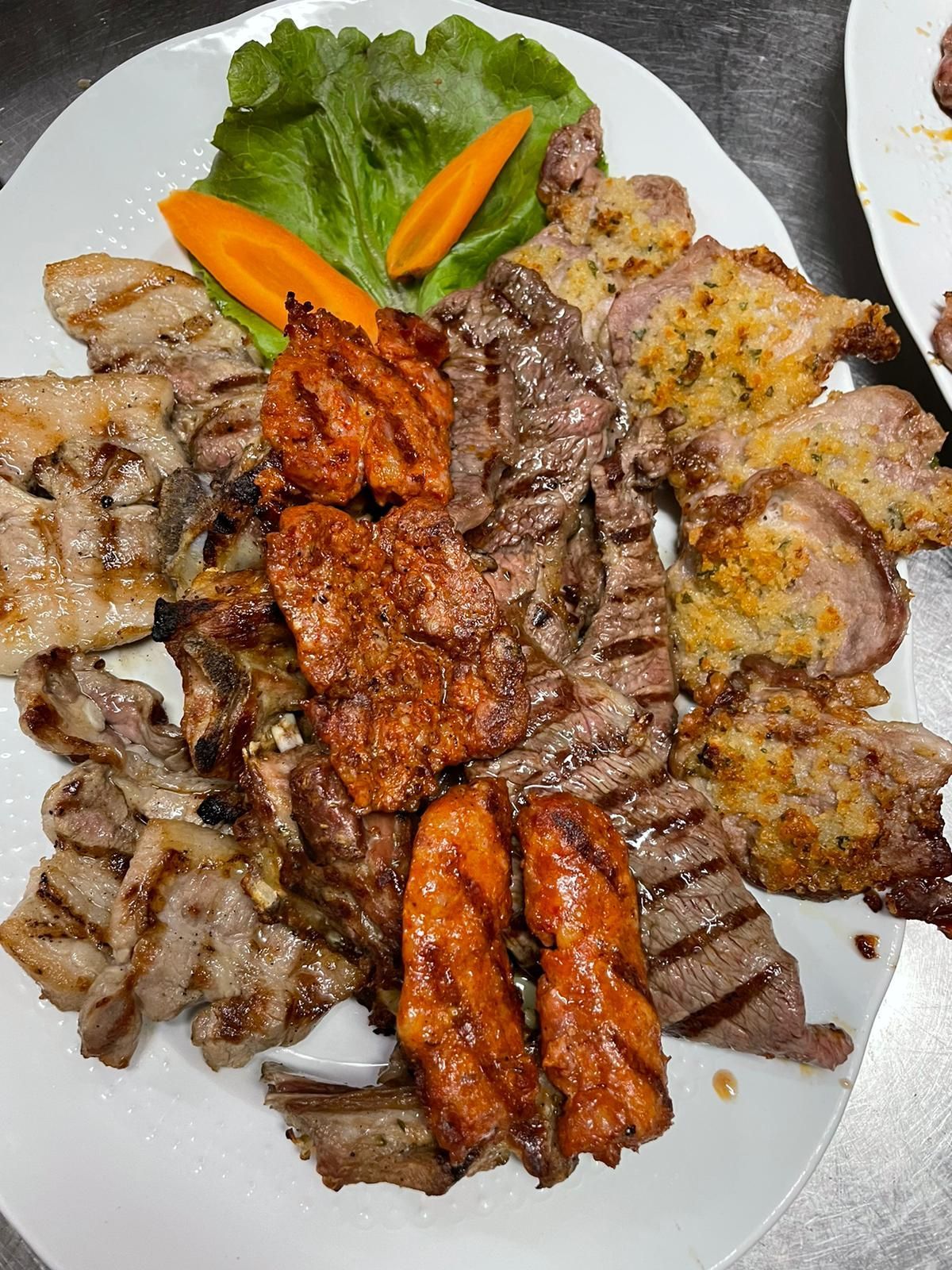Piatto di carne grigliata con verdure e lattuga su un piatto bianco