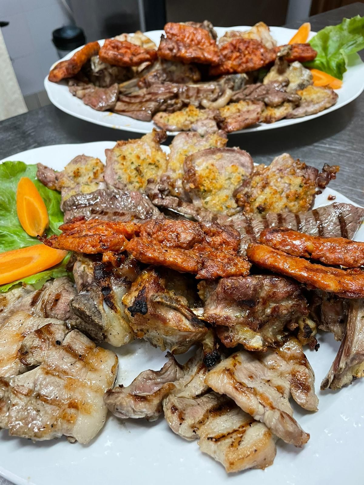 Piatti di spiedini di carne grigliata e pezzi arrostiti guarniti con carote e spicchi di limone su un tavolo