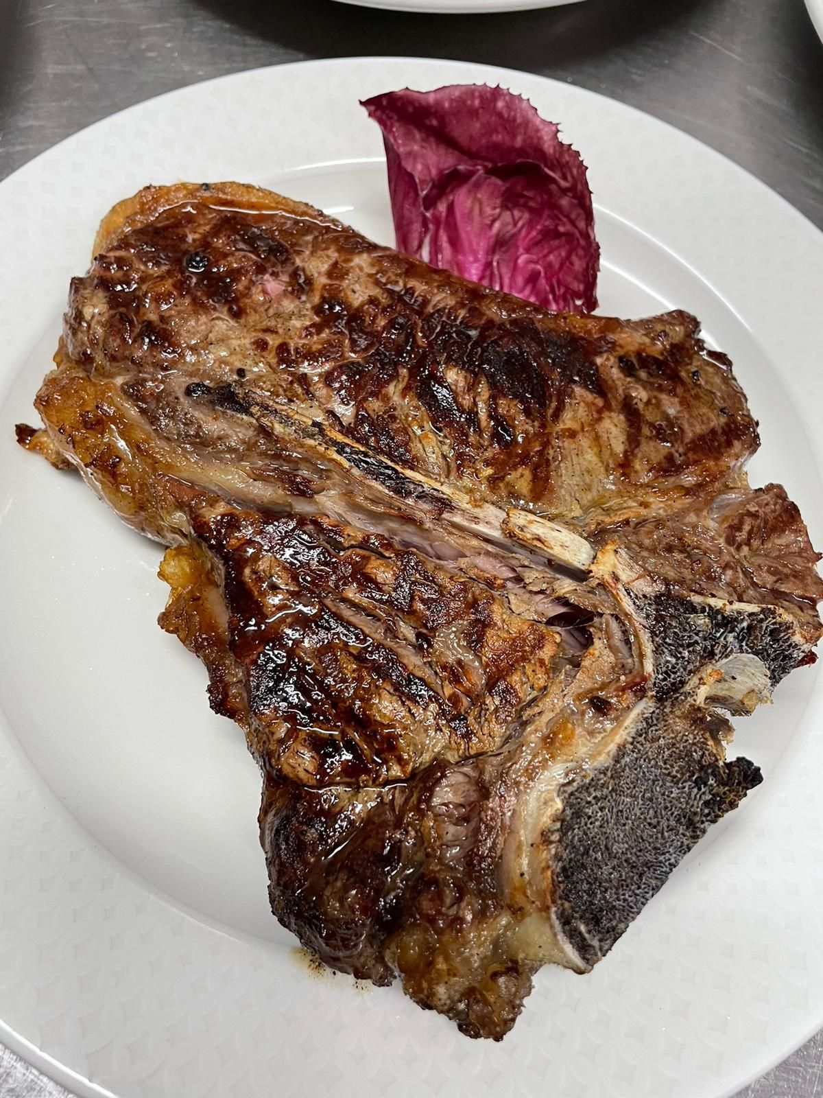 Bistecca alla griglia su un piatto bianco con uno spicchio di cavolo viola.