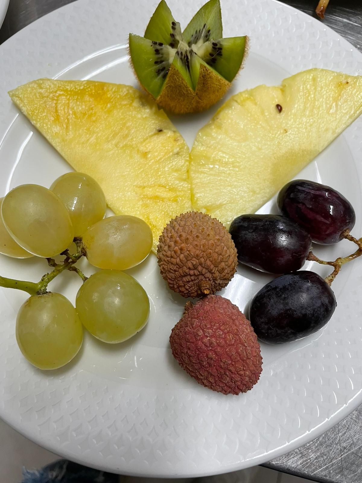 Piatto con fette di frutta assortita e uva disposte su un piatto bianco.