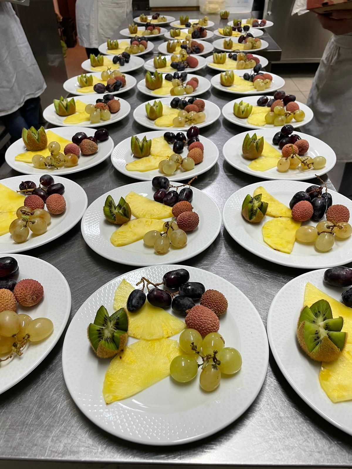 File di dessert a base di frutta, serviti su piatti bianchi, disposti su un tavolo da catering.
