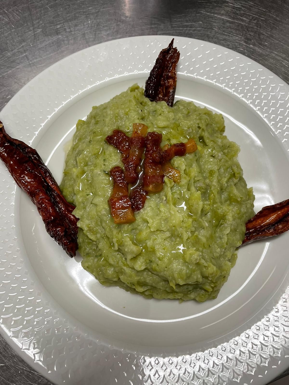 Un piatto di risotto verde condito con salsa rossa e guarnito con striscioline di peperone scuro arrostito.