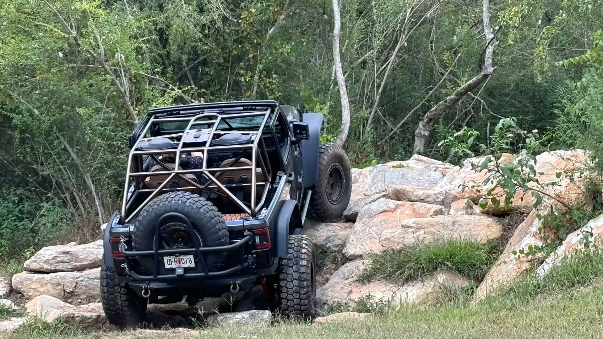 A jeep is driving down a rocky road in the woods.
