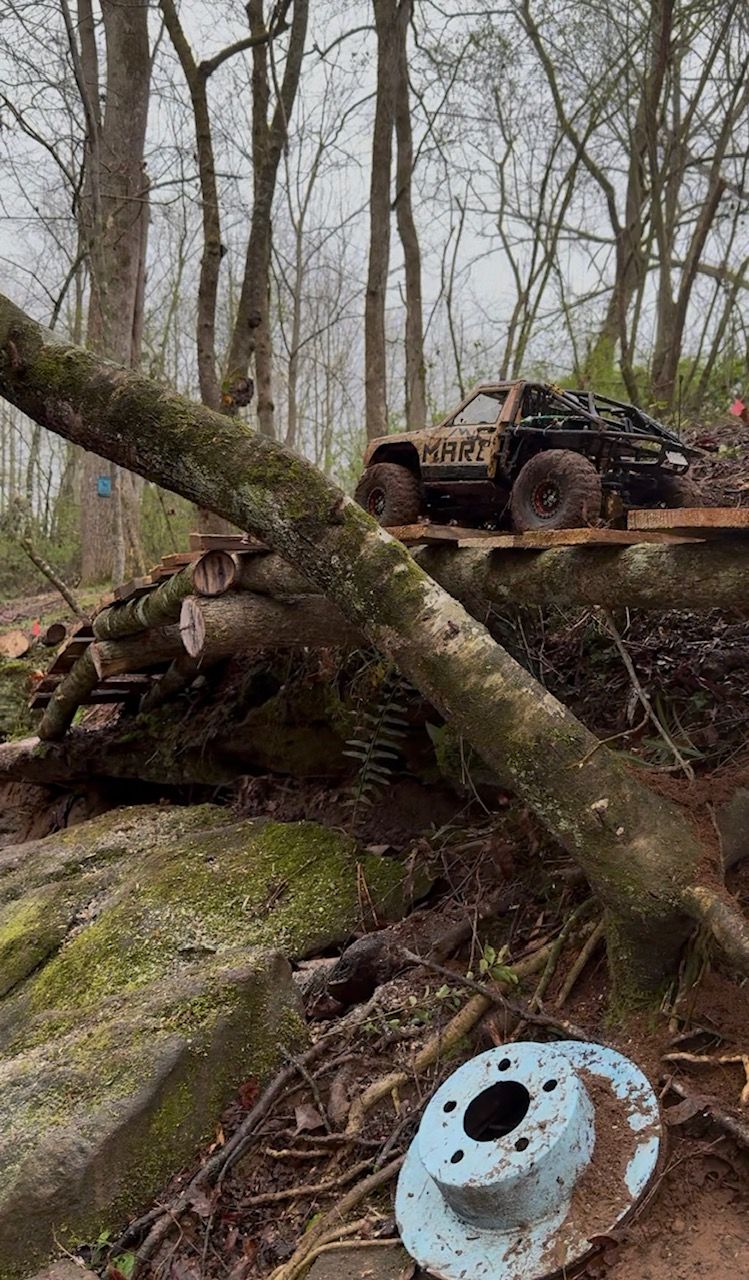 Off-road vehicle on a mossy forest embankment with fallen logs and bare trees