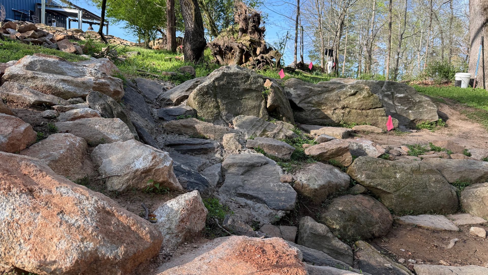 Rocky stone steps on a wooded hillside with trees and homes in the background
