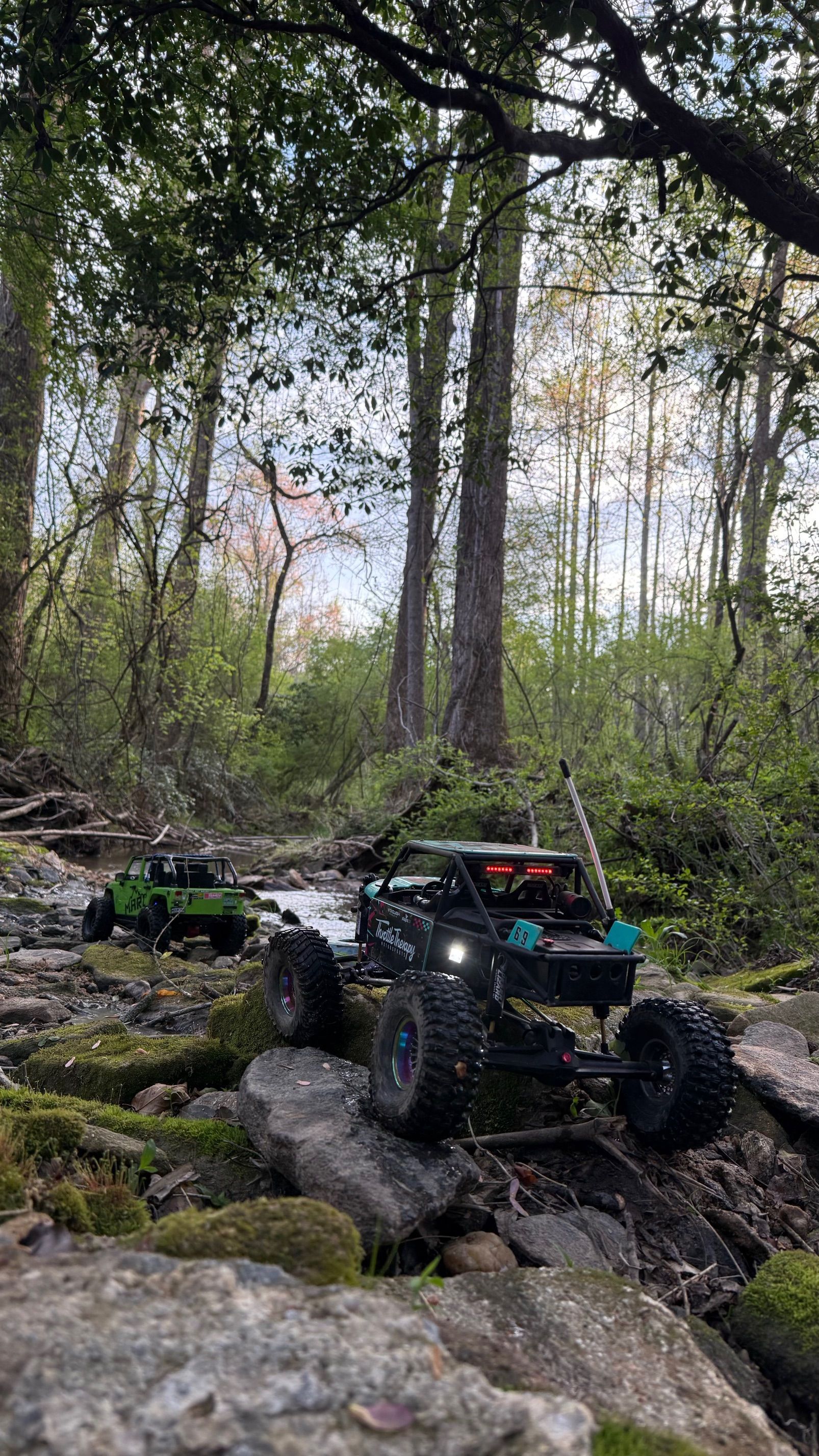 Off-road RC truck climbing rocks in a wooded forest trail