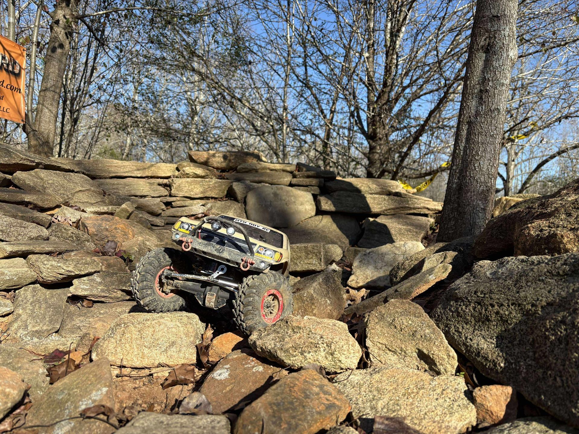 Remote-controlled off-road truck climbing rocks in a wooded streambed