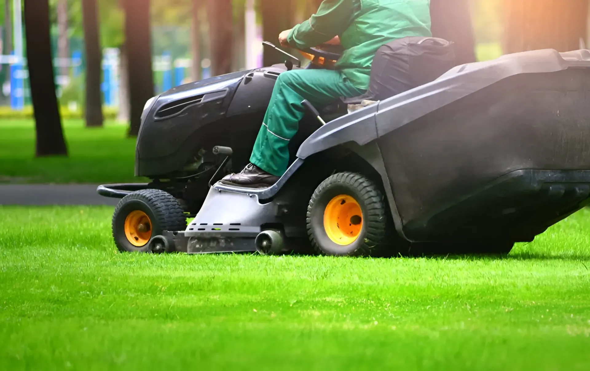 A Person in Green Overalls Operating a Black Riding Lawnmower — Garden City Slashing in Highfields, QLD