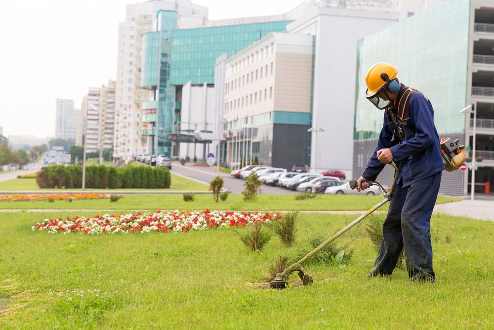 Man in Safety Gear Using a Weed Wacker on a City Lawn — Garden City Slashing in Highfields, QLD