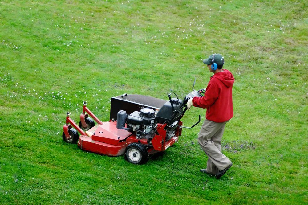 Person Mowing a Grassy Lawn With a Red Lawnmower — Garden City Slashing in Highfields, QLD