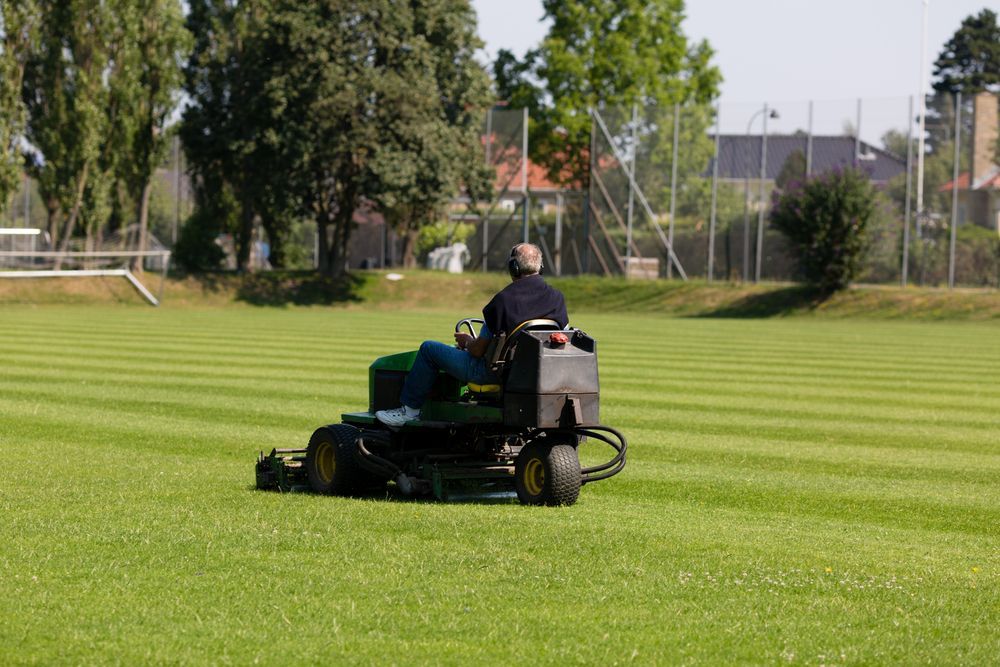 Man on a Riding Lawnmower Cutting Grass on a Green Field — Garden City Slashing in Toowoomba, QLD