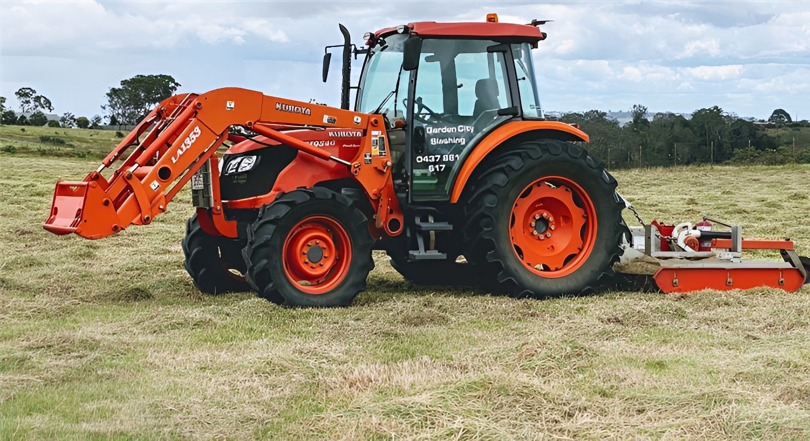 Orange Tractor With Front Loader and Mower in a Field — Garden City Slashing in Toowoomba, QLD