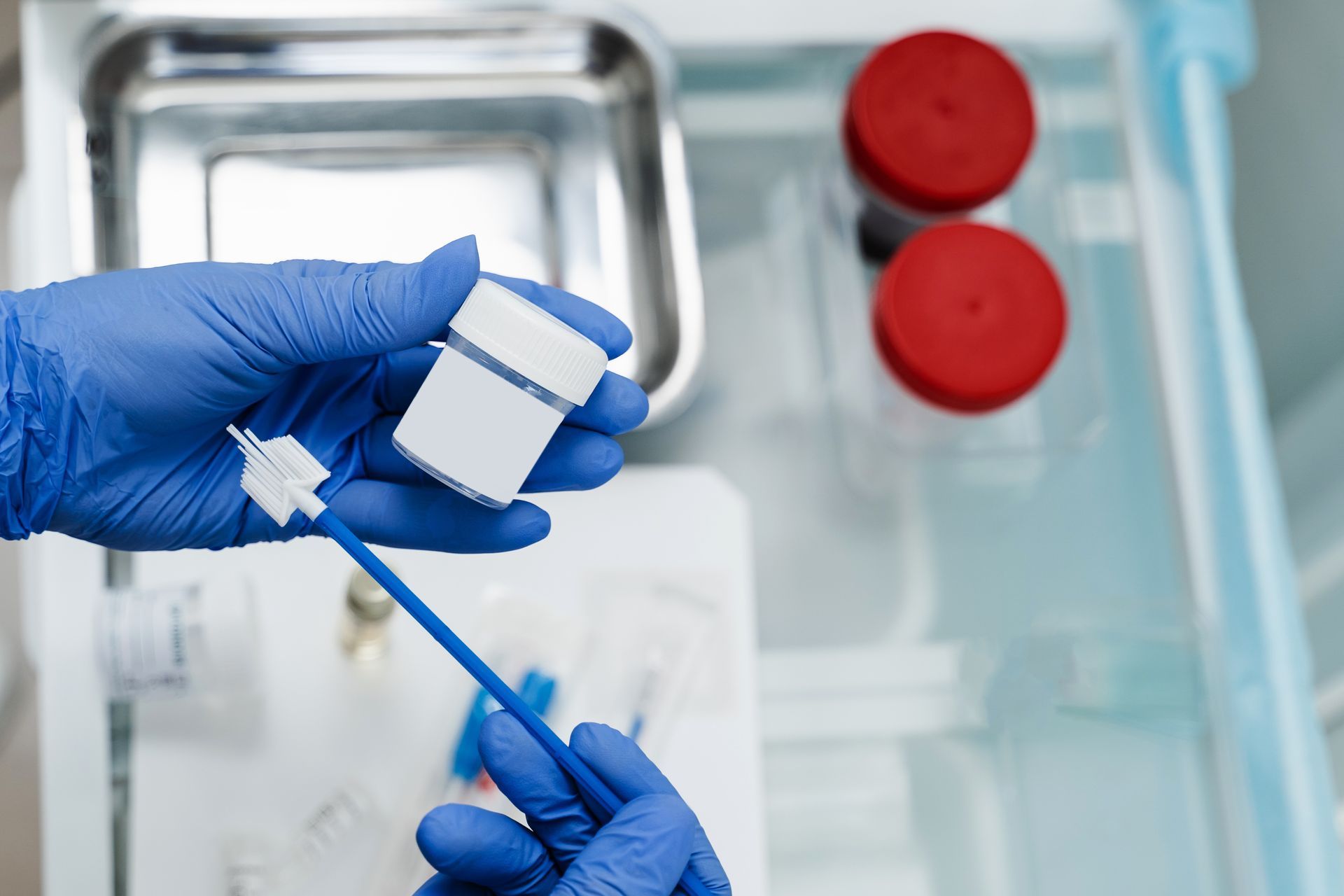 Gloved hands using a swab on a small white and blue device in a lab setting