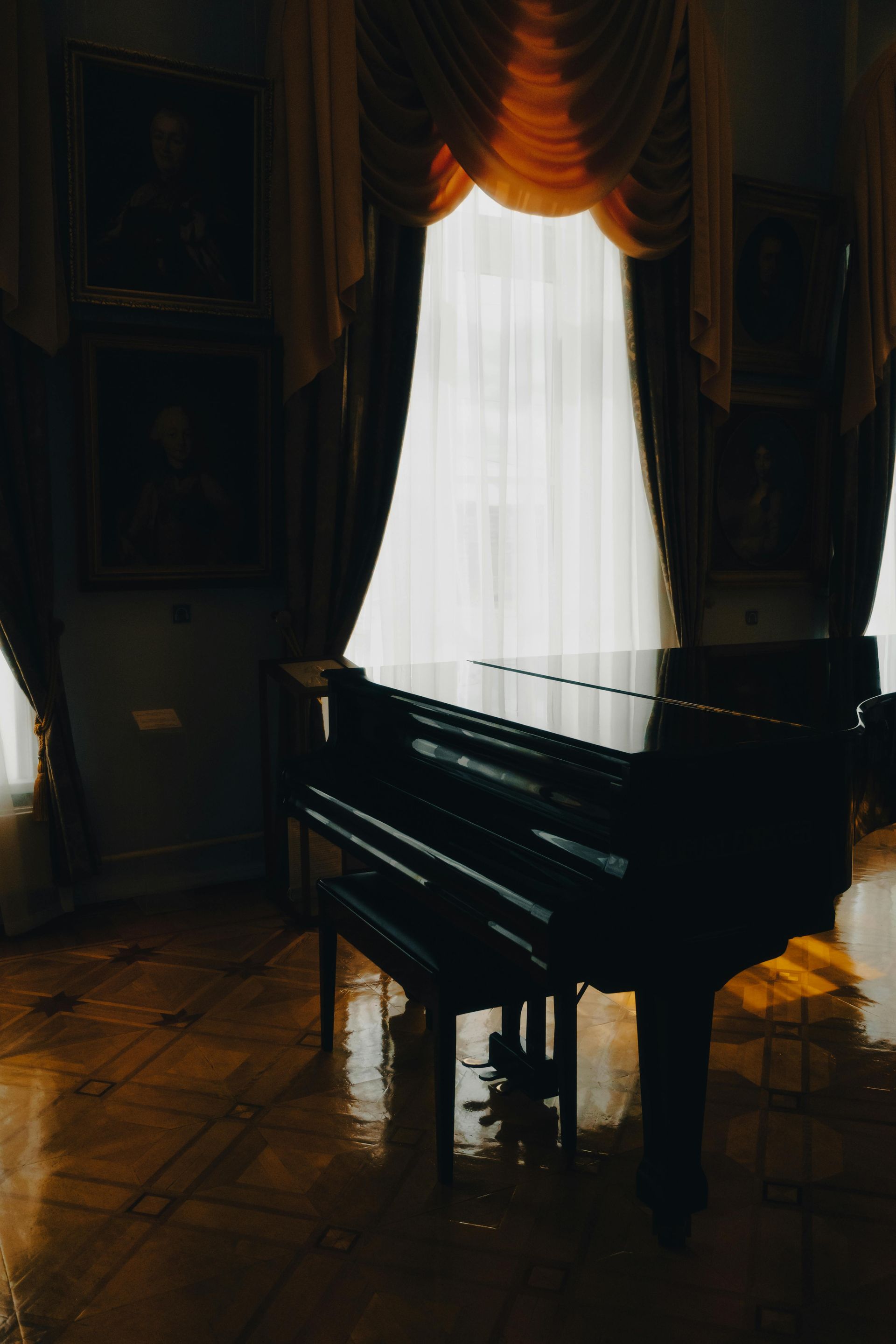 A grand piano is sitting in front of a window in a dark room.
