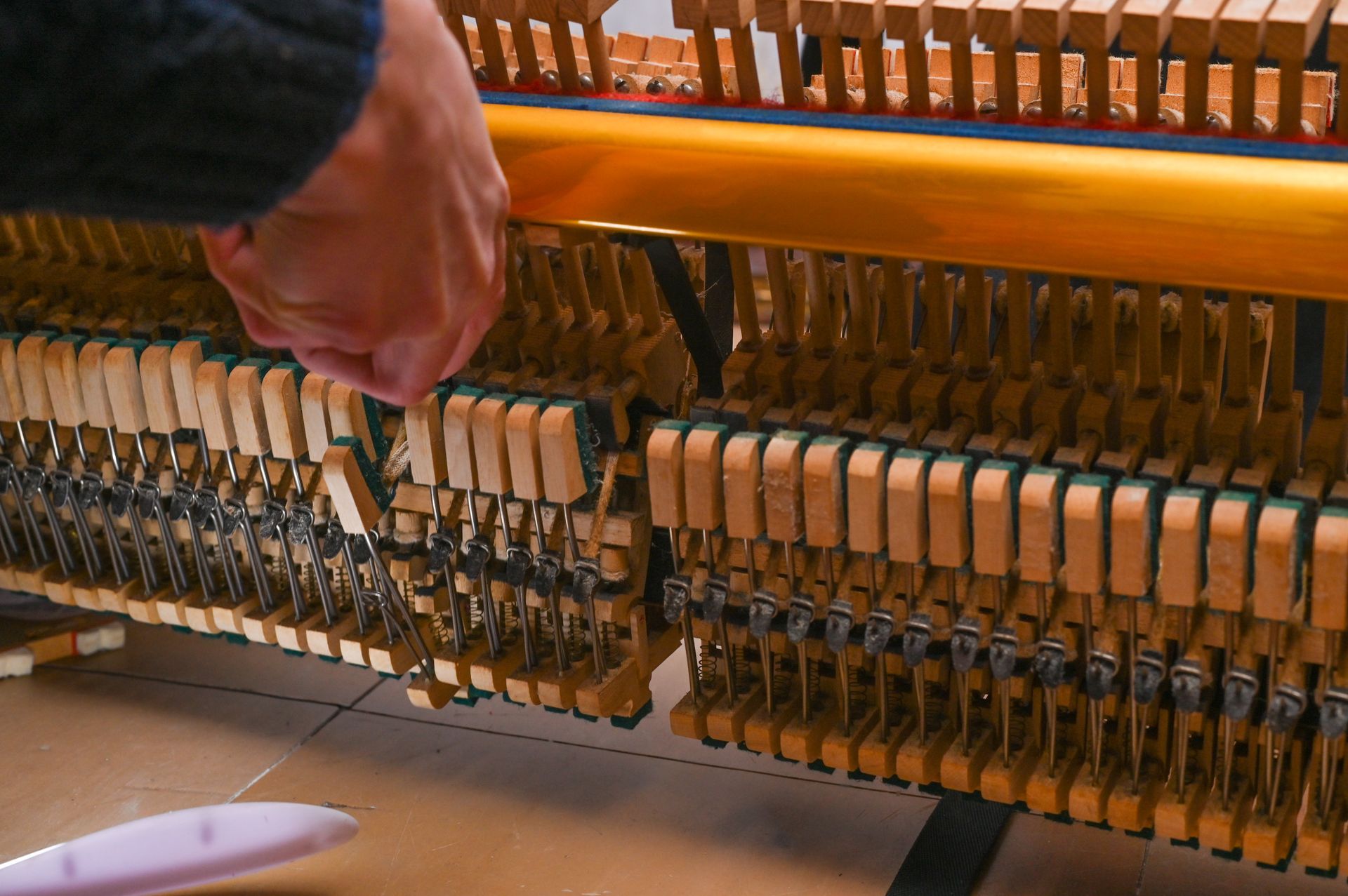 A person is cleaning a piano with a brush.