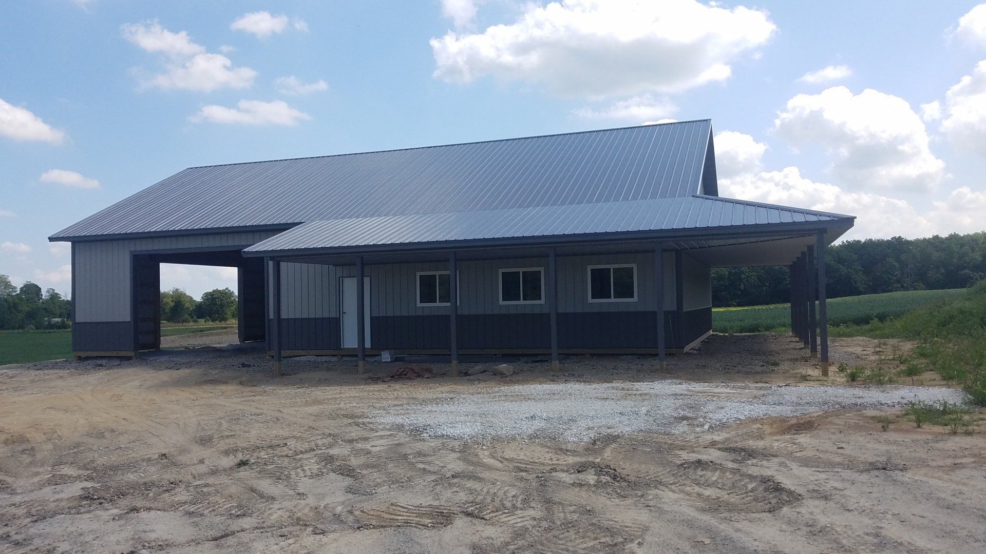 A gray and blue barn under construction on a sunny day.