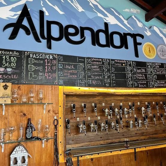Quadro de menu de bebidas alpinas de Alpendorf com torneiras e preços escritos à mão em lousa.