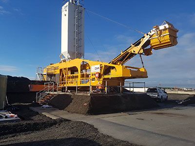 A large yellow machine is sitting on top of a pile of dirt.