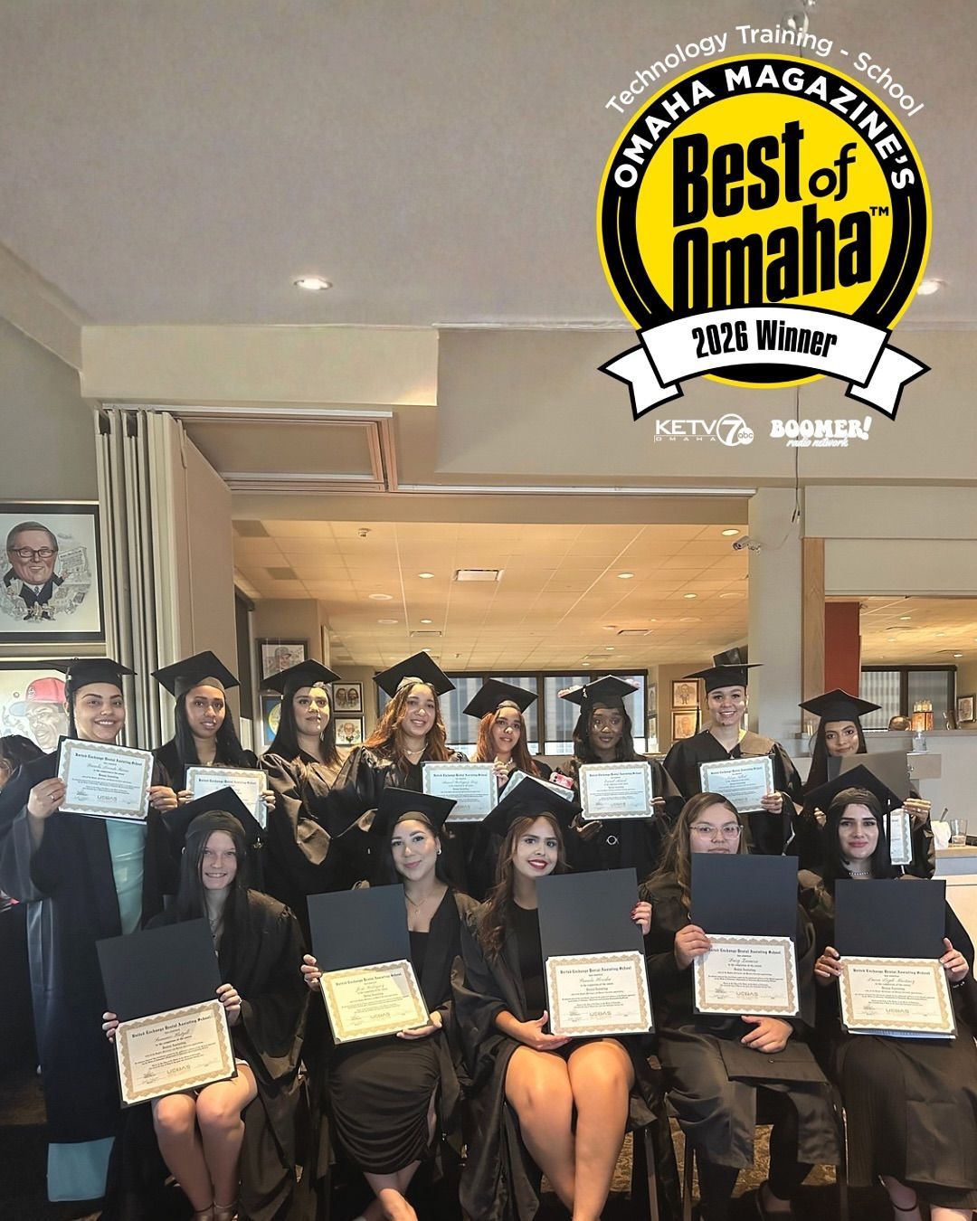 Group of graduates in caps and gowns holding certificates at an indoor award ceremony under a “Best of Omaha” sign