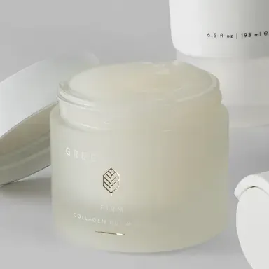 Cream-colored cosmetic jar with leaf logo on a white surface, next to a matching tube.