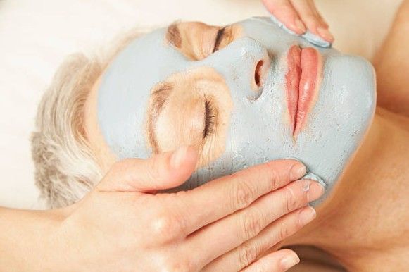 Woman receiving a blue facial mask and gentle massage at a spa