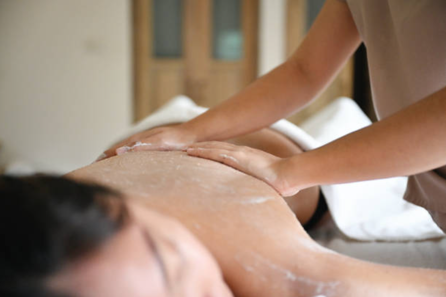 Hands massaging oil onto a person's back in a spa treatment room