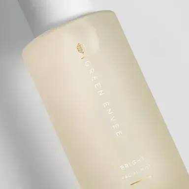 Cream-colored cosmetic bottle with gold lettering on a light background
