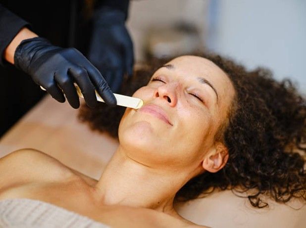 Gloved hand applying a facial treatment to a relaxed person lying on a spa bed