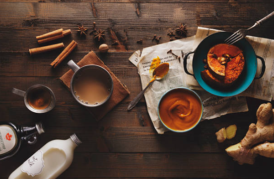 Overhead view of coffee, cinnamon sticks, and pastries on a rustic wooden table