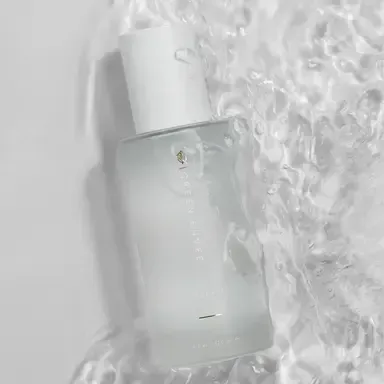 White cosmetic spray bottle on a clear, crinkled surface