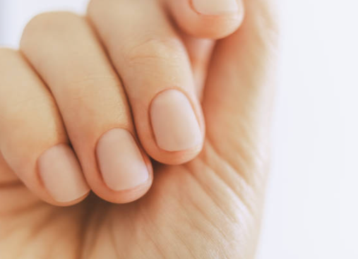 Close-up of a hand with neatly trimmed nails resting against a light background
