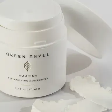 Green Envee Nourish vegan moisturizer jar on a white surface with cream swatches