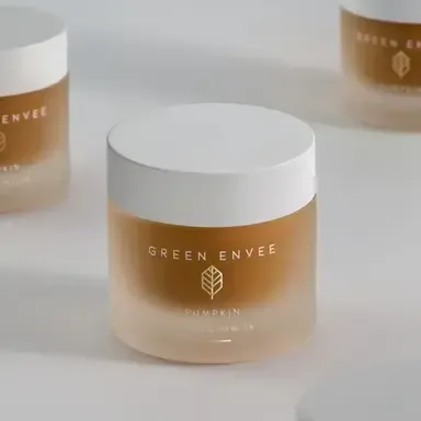 Three frosted cream jars with white lids, labeled Green Envee, on a light gray surface