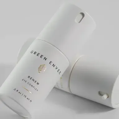 Two white cosmetic tubes with green branding on a light gray background