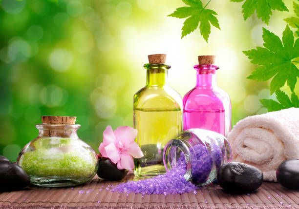 Spa still life with colorful massage oils, towels, lavender, stones, and green leaves on a bamboo mat